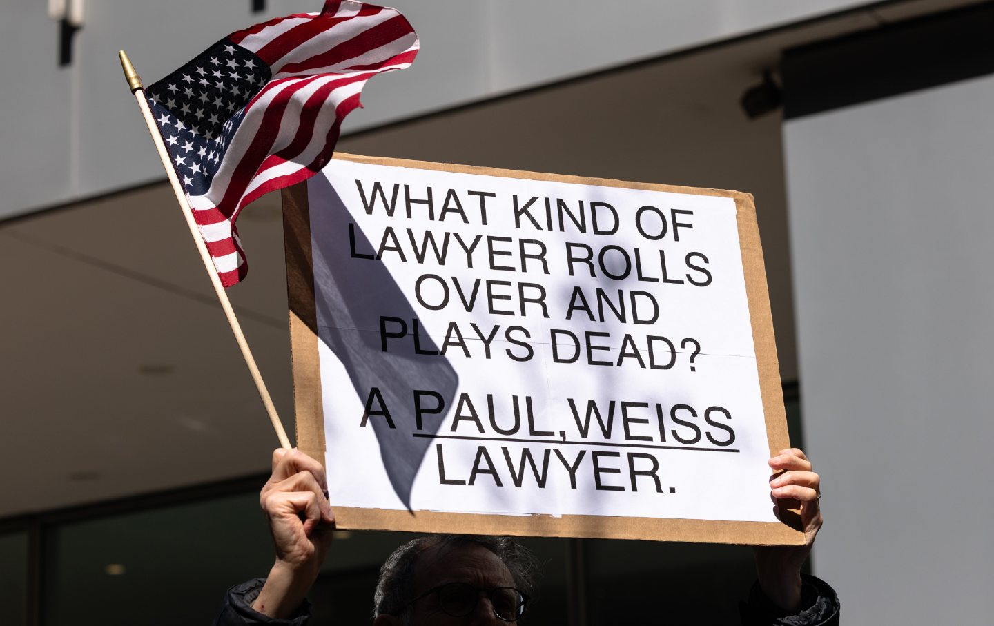 A man holding up a US flag and a sign that reads, 