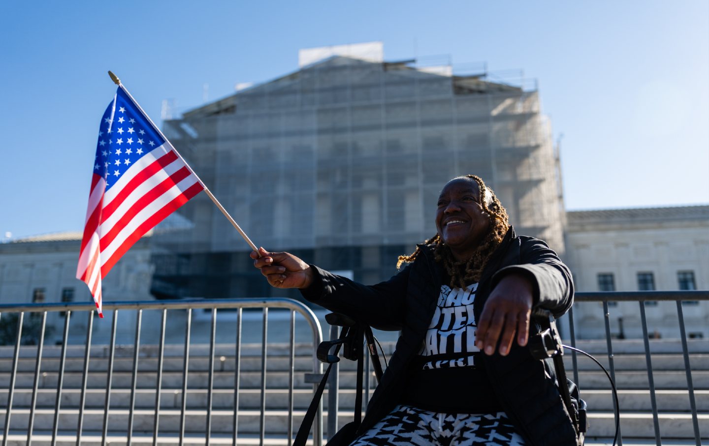 A woman held a US flag outside the Supreme Court as the court weighed the future of the Voting Rights Act on October 15, 2025.