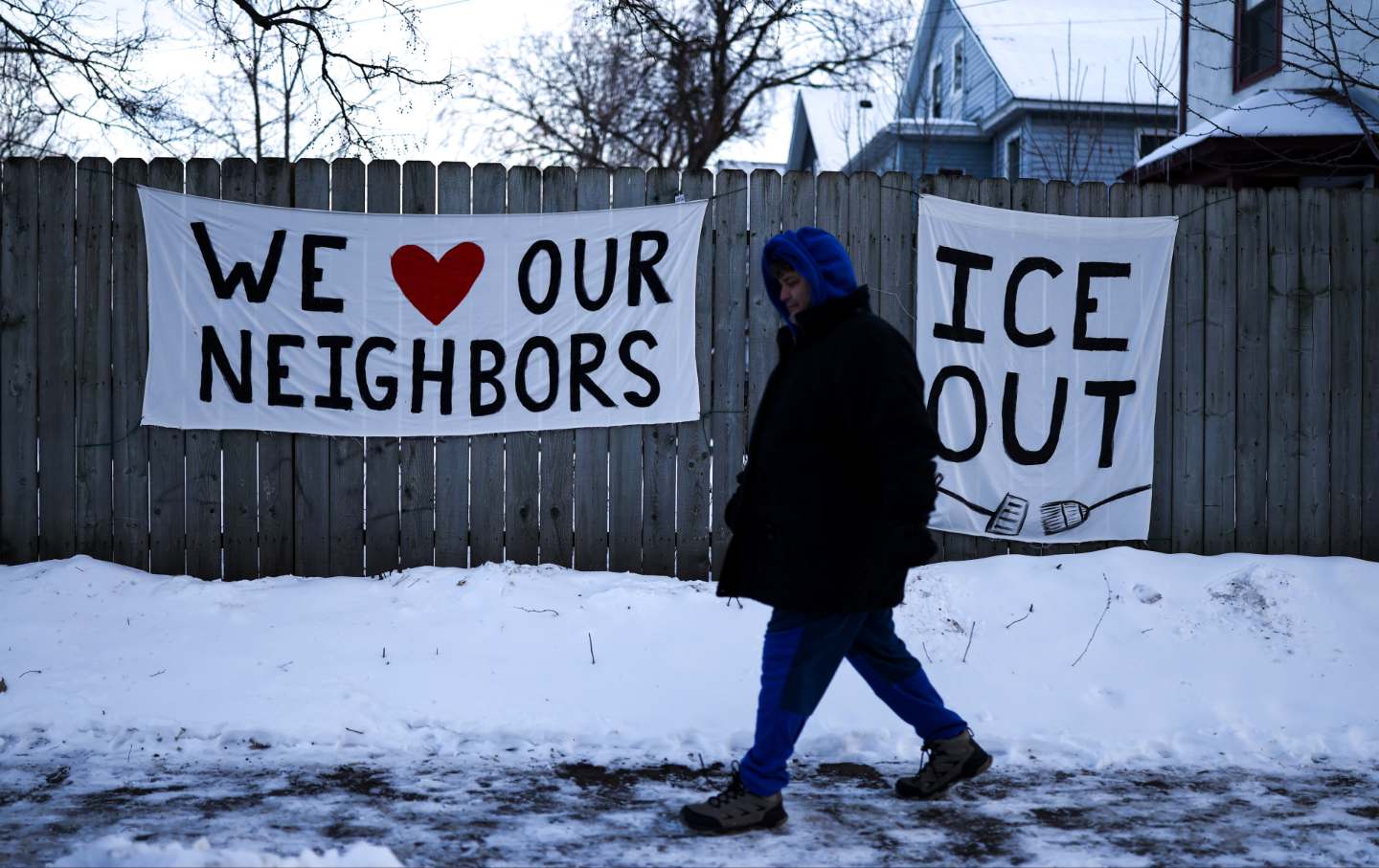 A man walks past signs hanging on a fence in Minneapolis, Minnesota, on February 3, 2026.