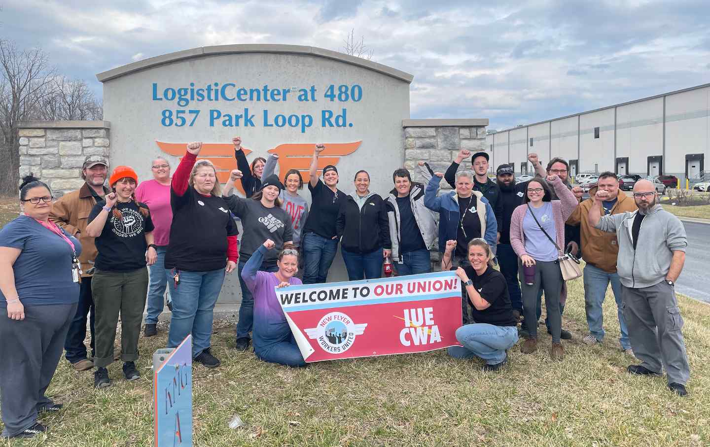 A group of workers stand behind a banner reading 