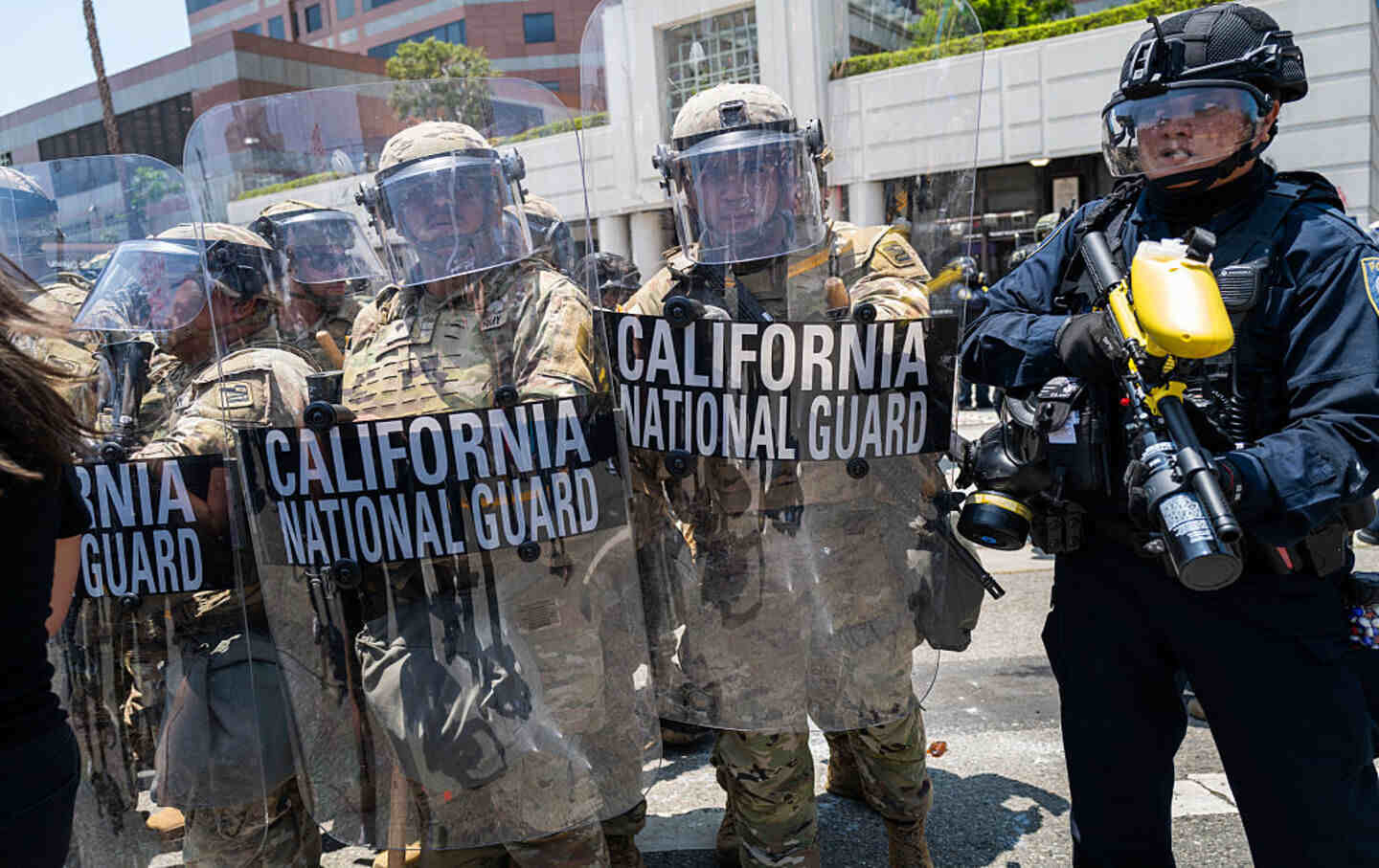LAPD officers and National Guard soldiers stand outside a downtown LA jail in June 2025.